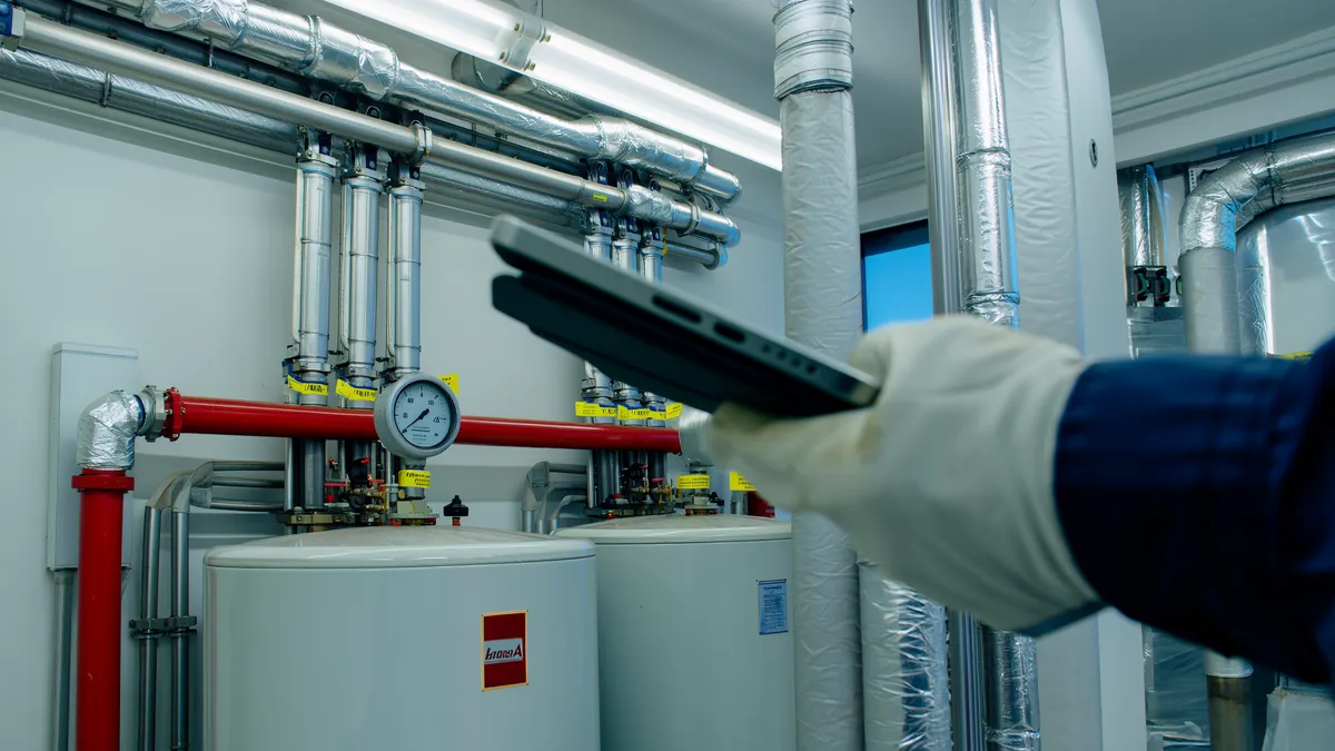 A maintenance engineer with a tablet in a plant room